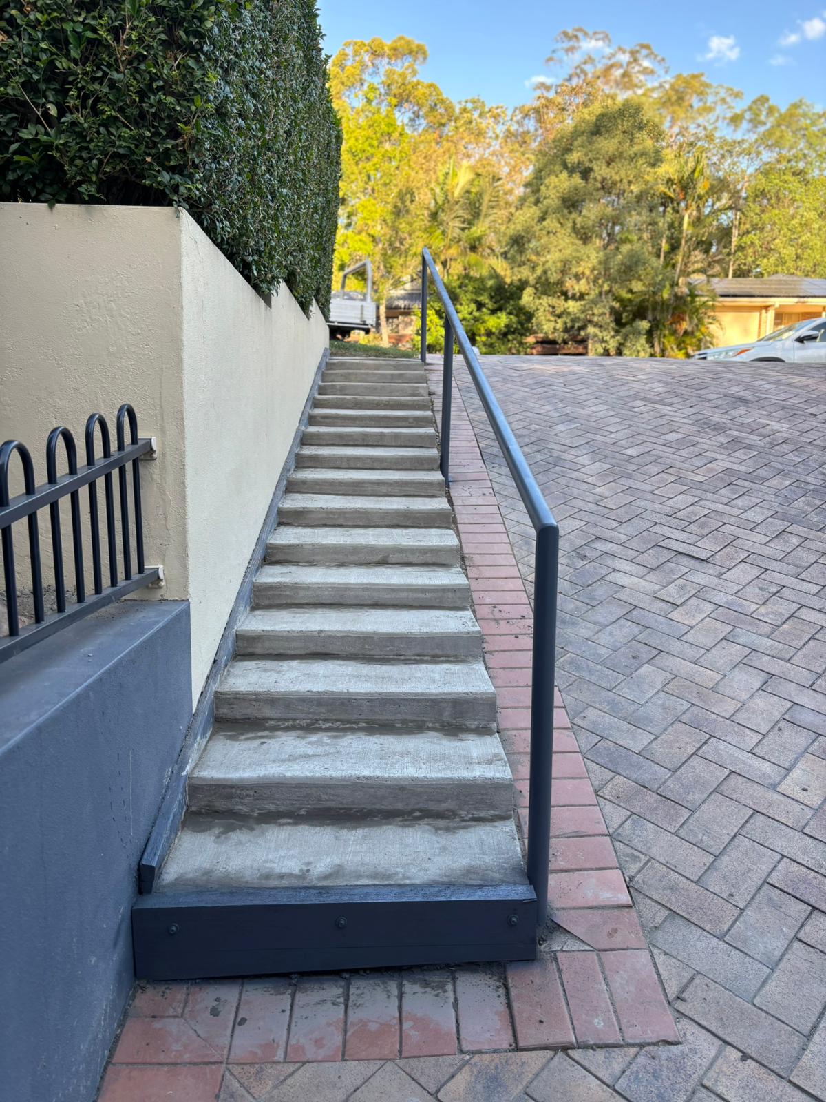 Outdoor concrete steps with handrail and paving