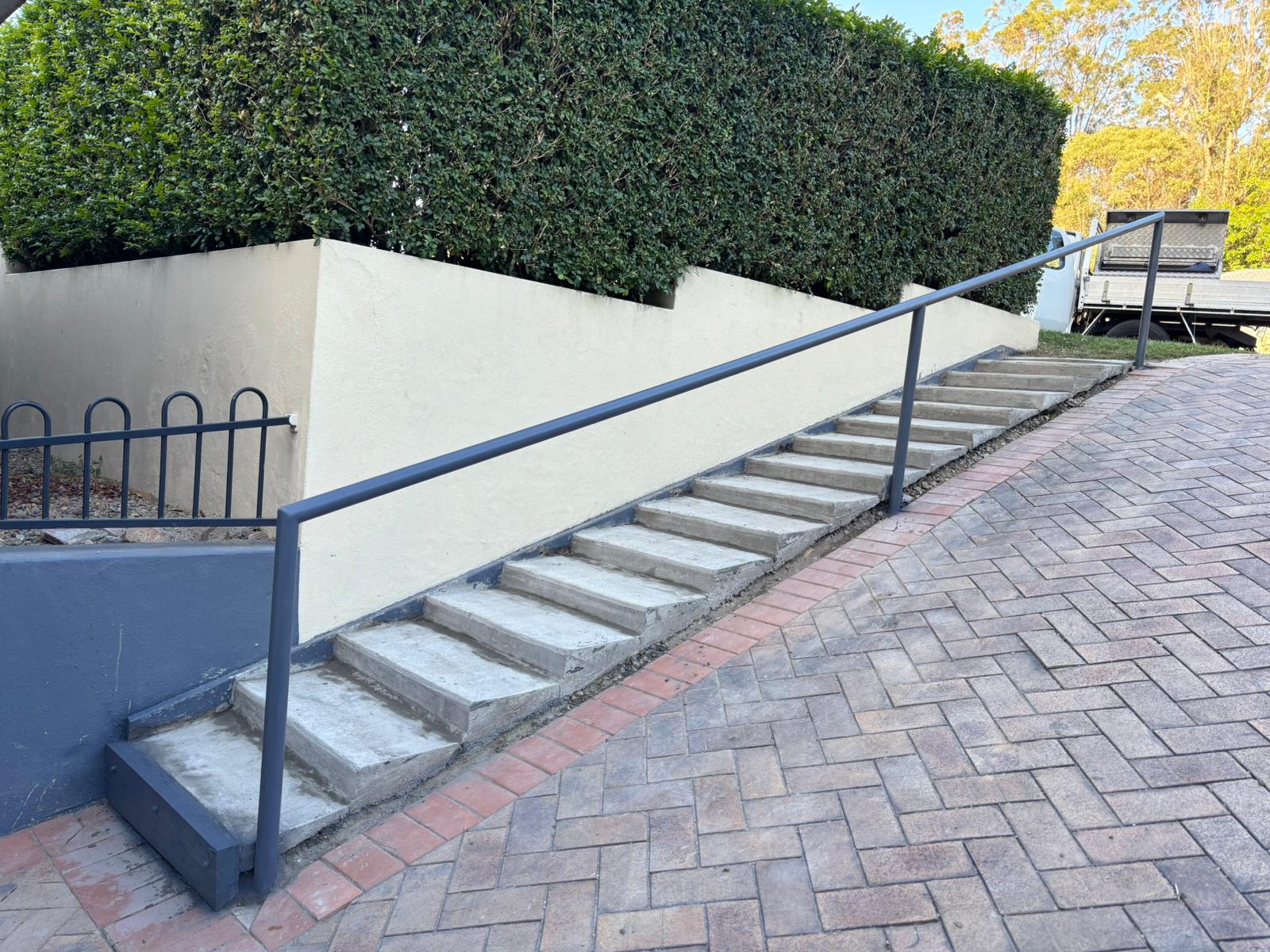 Concrete stairs with handrail and rendered wall